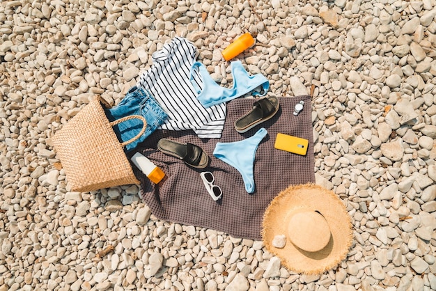 Vista aérea de la manta de cosas de playa con sombrero de paja de crema de protección solar con bolsa