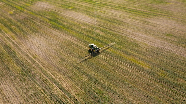 Vista aérea de la máquina de pulverización trabajando en el campo verde.