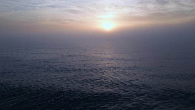 Vista aérea de un mar al amanecer con una manta de niebla matutina y rayos de sol matutinos brillando a través