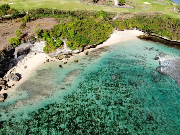 Vista aérea del mar azul con acantilado rocoso en la costa arenosa de Bali