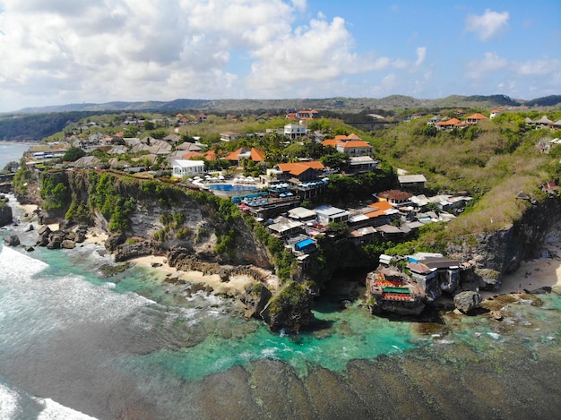 Vista aérea del mar azul con acantilado rocoso en la costa arenosa de Bali