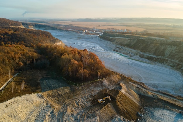 Vista aérea de la mina a cielo abierto de materiales de piedra arenisca para la industria de la construcción con excavadoras y volquetes. Equipo pesado en minería y producción de minerales útiles concepto