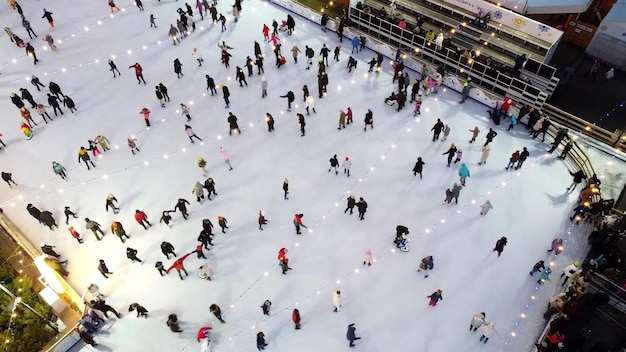 Vista aérea de muchas personas patinando en una pista de hielo al aire libre en invierno patinaje sobre hielo vista superior hielo del parque de la ciudad