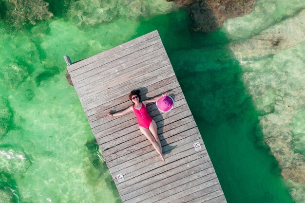 Vista aérea de la mujer acostada en el muelle de madera en un día soleado de verano en cancún méxico vista superior joven sexy