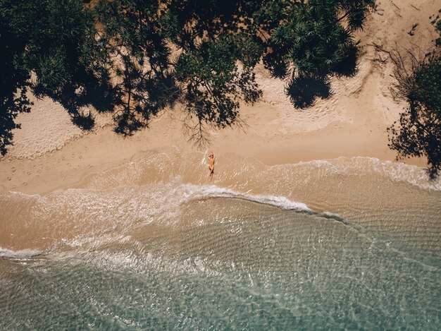 Vista aérea de la mujer acostada en la playa. Mujer joven en el mar. Phuket. Tailandia Vista superior. Paisaje marino con niña en la orilla del mar, agua azul y olas. Viajar