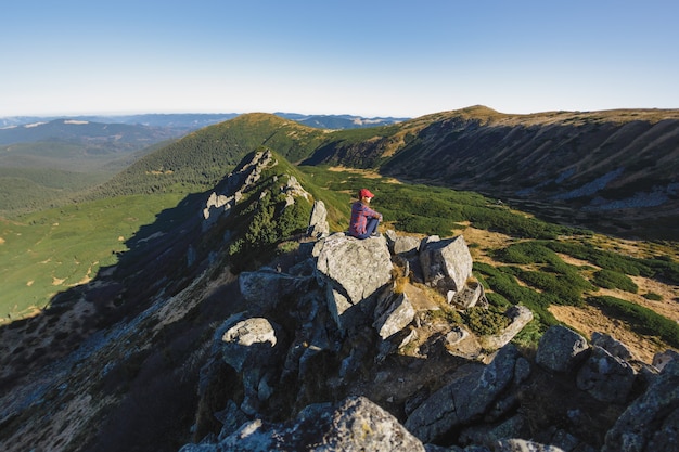Vista aérea de la mujer excursionista relajándose en la cima de una montaña y disfrutando del concepto de vista al valle de
