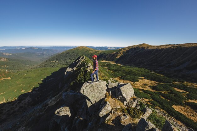 Vista aérea de la mujer excursionista relajándose en la cima de una montaña y disfrutando del concepto de vista al valle de