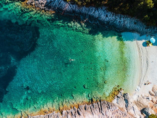 Vista aérea de la mujer flotando en la espalda en vacaciones de Grecia de agua de mar clara