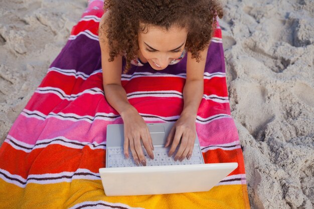 Vista aérea de una mujer joven que usa su computadora portátil en su toalla de playa