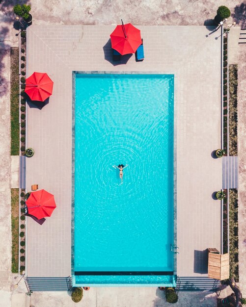 Foto vista aérea de una mujer joven relajándose en la piscina