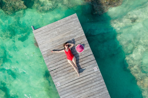 Vista aérea de la mujer tendida en el muelle de madera en un día soleado de verano en la vista superior de cancún méxico joven sexy