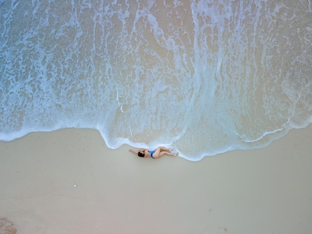 Vista aérea de la mujer en traje de baño azul en la playa de mar hermosas olas