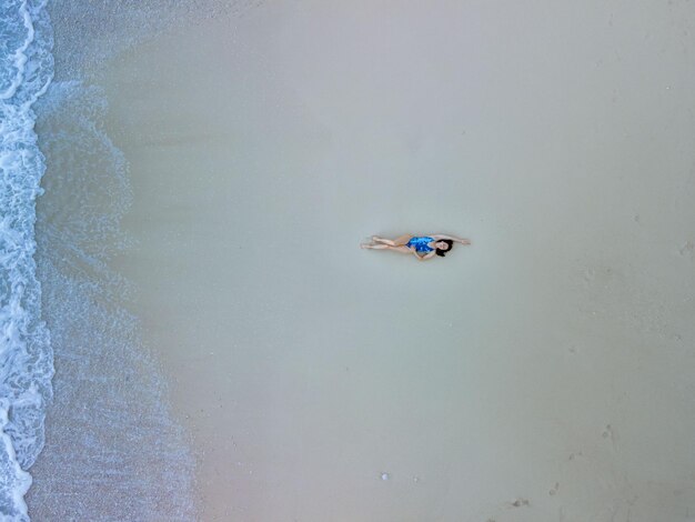 Vista aérea de la mujer en traje de baño azul en la playa del mar