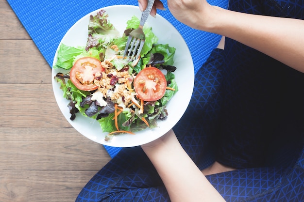 Vista aérea de mujer de yoga comiendo ensalada fresca, comer sano y elaborar concepto