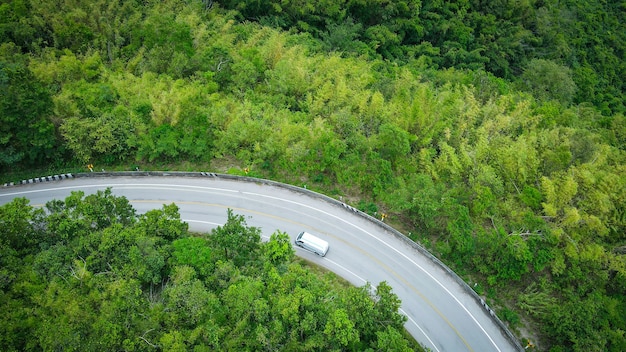 Vista aérea de la naturaleza del bosque con el coche en la carretera en la curva de la carretera de la vista superior del árbol verde de la montaña