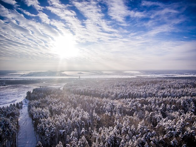 Vista aérea neve inverno floresta campo perto da estrada Rio congelado Nuvens com sol no céu azul