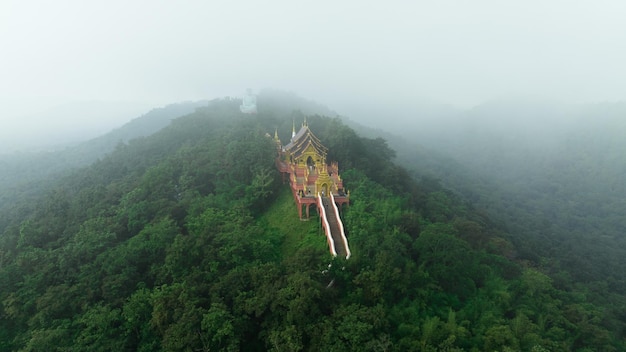 Vista aérea en la niebla de la mañana Wat Phra That Doi Phra Chan y Daibutsu Buddha en la montaña verde