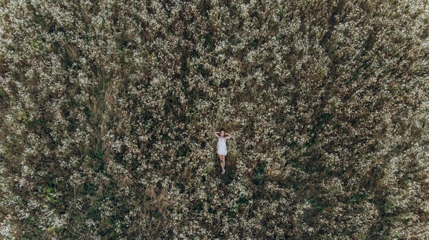 Vista aérea de una niña acostada en un campo de flores y relajante