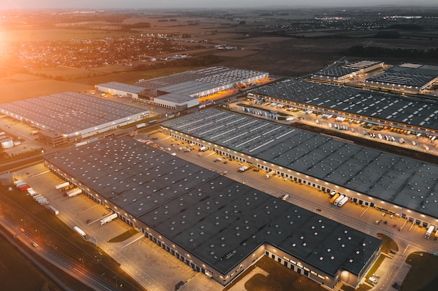 Vista aérea nocturna de un almacén de mercancías para tiendas online. Centro logístico en el polígono industrial de la ciudad desde arriba.