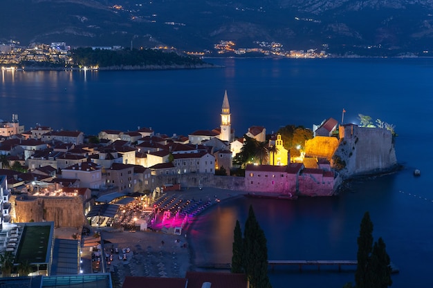 Vista aérea noturna das igrejas de São Ivan e da Santíssima Trindade na cidade velha de Budva, cidade montenegrina, no Mar Adriático, Montenegro