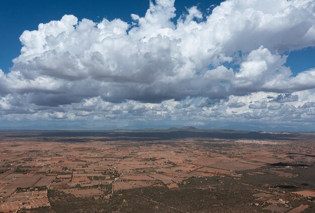 Vista aérea de las nubes proyectando sombras sobre el campo con las montañas al fondo