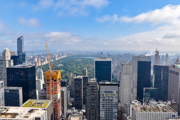 Vista aérea de Nueva York con rascacielos, edificios en construcción y Central Park al fondo. Día soleado con algunas nubes. Concepto de viaje y construcción. Nueva York, Estados Unidos.