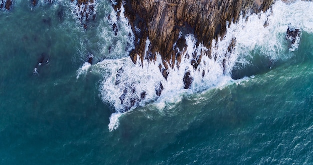 Vista aérea de las olas rompiendo en las rocas, paisaje marino con vista de pájaro