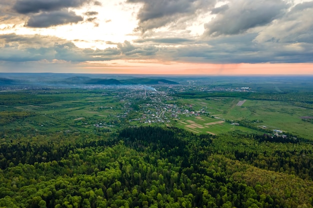 Vista aérea de las oscuras colinas de las montañas cubiertas de pinos verdes mixtos y frondosos bosques en la noche.