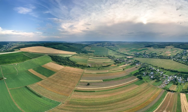 Vista aérea del paisaje de campos agrícolas cultivados verdes y amarillos con cultivos en crecimiento en un brillante día de verano