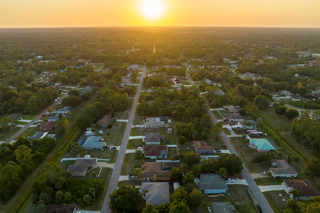 Vista aérea del paisaje de casas privadas suburbanas entre palmeras verdes en la zona rural tranquila de Florida al atardecer