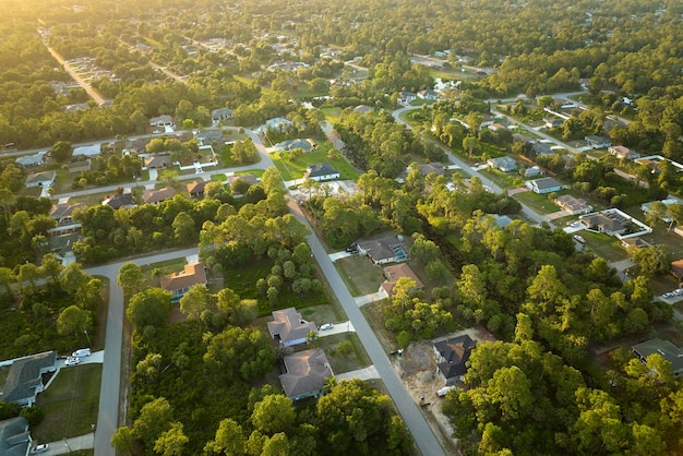 Vista aérea del paisaje de casas privadas suburbanas entre palmeras verdes en la zona rural tranquila de Florida al atardecer