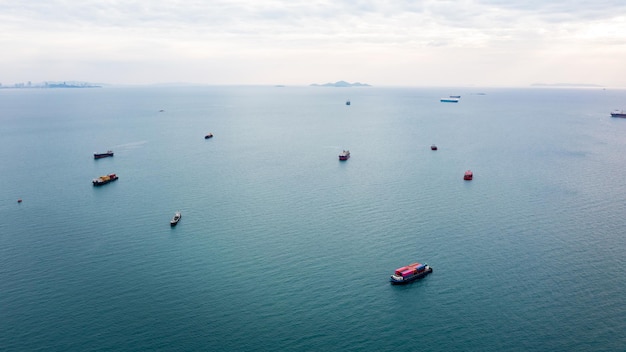 Vista aérea del paisaje marino y un pequeño barco de contenedores flotando en el horizonte marino y el fondo del cielo nublado al atardecer en Tailandia