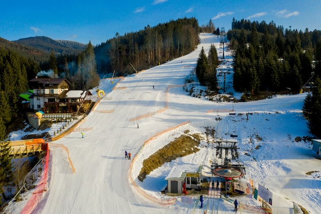 Vista aérea del paisaje de pistas de esquí y snowboard a través de pinos que descienden a la estación invernal de los Cárpatos