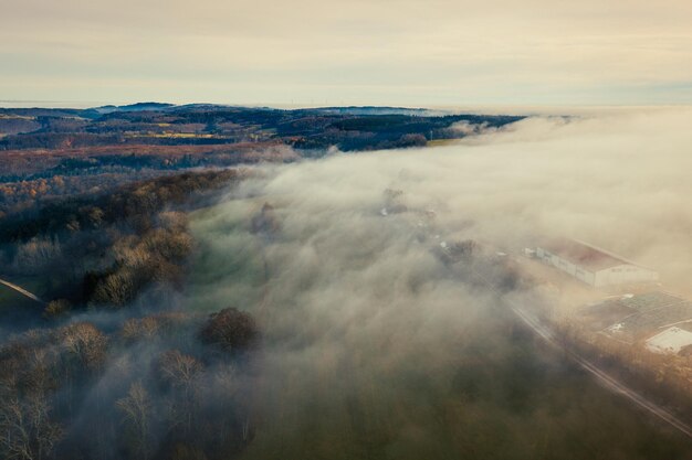 Vista aérea del paisaje rural y la granja en la niebla de invierno en una atmósfera de mal humor