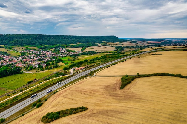 Vista aérea de pájaro de los típicos prados de campo verde de las Ardenas y el paisaje de la colina que también muestra la carretera y los edificios en el fondo lejano de este entorno alemán Alemania