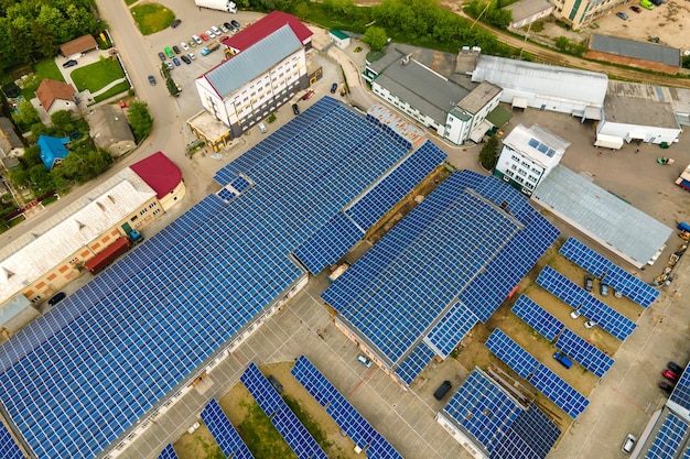 Vista aérea de paneles solares fotovoltaicos azules montados en el techo de un edificio industrial para producir electricidad ecológica limpia. Producción de concepto de energía renovable.