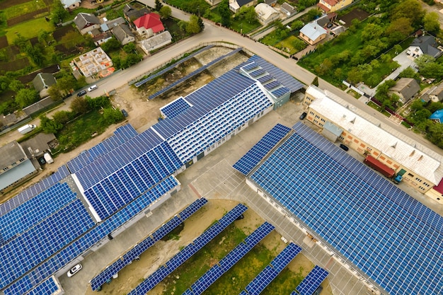 Vista aérea de paneles solares fotovoltaicos azules montados en el techo de un edificio industrial para producir electricidad ecológica limpia. Producción de concepto de energía renovable.