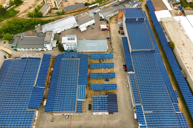 Vista aérea de paneles solares fotovoltaicos azules montados en el techo de un edificio industrial para producir electricidad ecológica limpia. Producción de concepto de energía renovable.