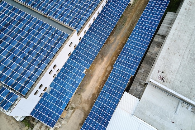 Vista aérea de paneles solares fotovoltaicos azules montados en el techo de un edificio industrial para producir electricidad ecológica verde. Producción del concepto de energía sostenible.