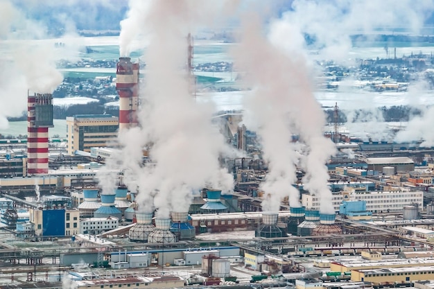 Vista aérea panorámica invernal del humo de las tuberías de una planta química o empresa de carpintería Concepto de contaminación del aire y el agua