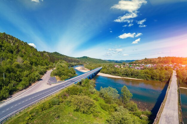 Vista aérea panorámica del valle de las montañas con el río del pueblo y dos puentes de carretera