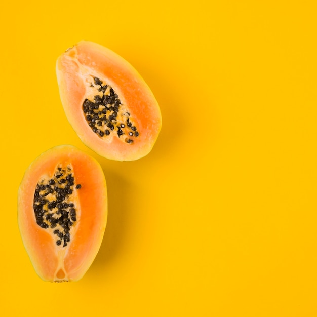 Una vista aérea de papaya a la mitad con semillas sobre fondo amarillo