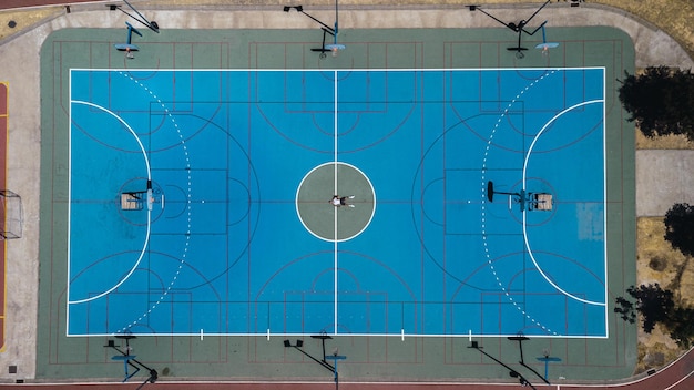 Vista aérea de un patio de juegos de baloncesto azul rodeado de árboles