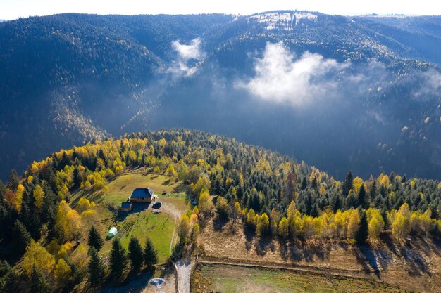 Vista aérea de una pequeña granja y un colorido bosque de otoño