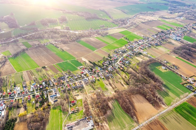 Vista aérea de un pequeño pueblo entre campos verdes un pequeño pueblo una calle larga y muchas casas privadas paisaje