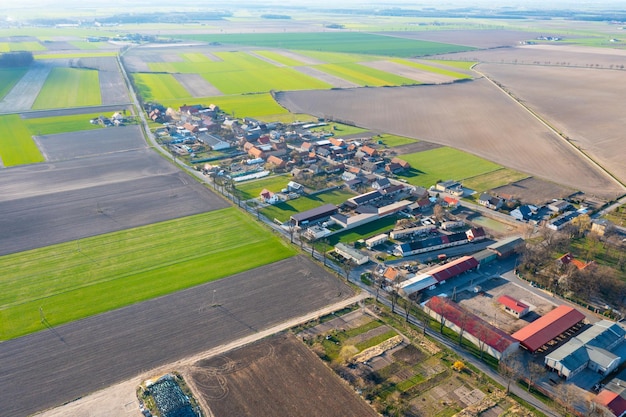 Vista aérea de un pequeño pueblo entre campos verdes un pequeño pueblo una calle larga y muchas casas privadas paisaje