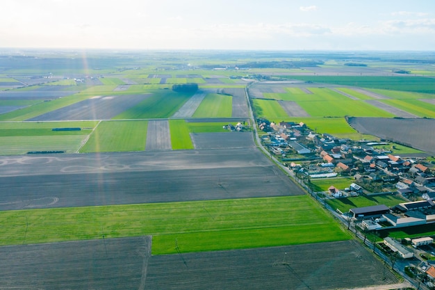 Vista aérea de un pequeño pueblo entre campos verdes un pequeño pueblo una calle larga y muchas casas privadas paisaje