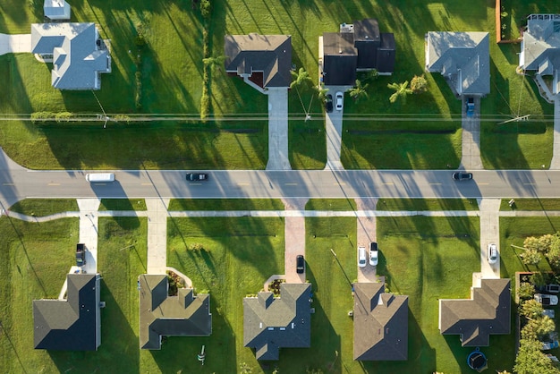 Vista aérea de un pequeño pueblo estadounidense en Florida con casas privadas entre palmeras verdes y calles suburbanas en una tranquila zona residencial