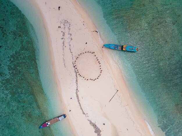 Vista aérea de personas en una playa con botes al fondo