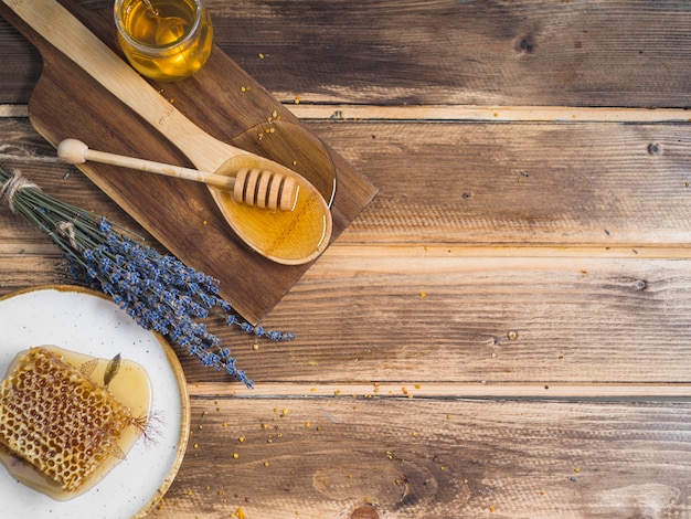 Foto una vista aérea de una pieza de panal de abeja; lavanda y miel en la mesa de madera